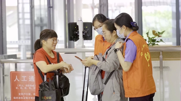 在崇左南站候车室，“刘三姐·青甜”志愿服务队为旅客答疑解惑。李伊摄