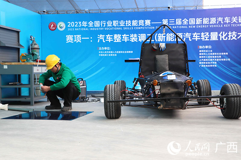 汽车整车装调工项目比赛现场，参赛选手正在动手完善参赛新能源汽车。人民网 付华周摄