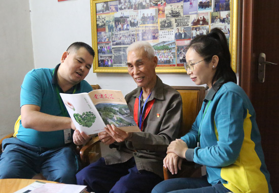 杨光辉与投递员一同阅读《党建文汇》。贵港市邮政分公司供图