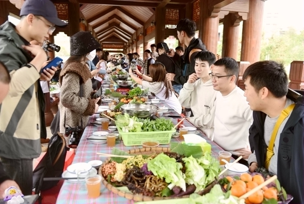游客品尝簸箕长桌宴美食。黄燕群摄