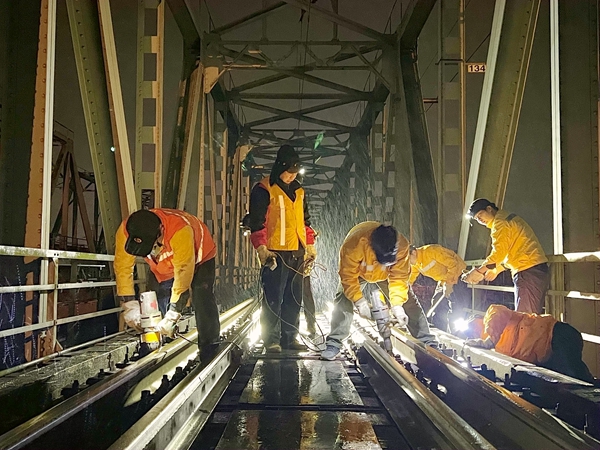 玉林工务段职工冒着寒风冷雨在铁路桥上进行设备整修作业。梁国鑫摄