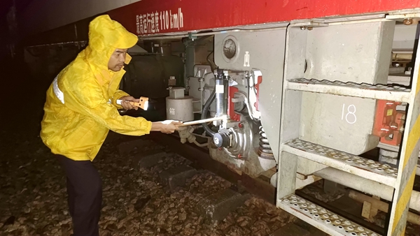 轨道车司机冒雨检查轨道车辆设备和走行部位，做好出车运输准备工作。张业深摄