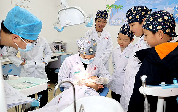 图为口腔医生为“小牙医” 现场教学口腔检查。唐侃摄