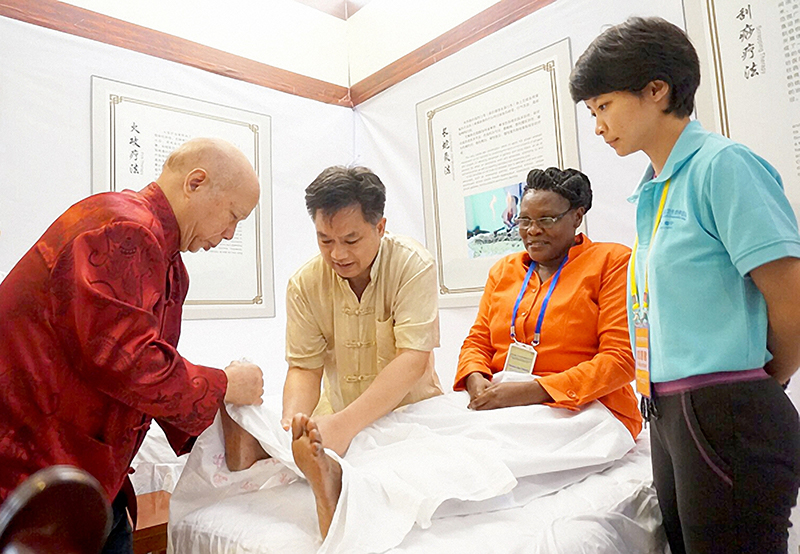 韦贵康（左一）为患者治疗。广西中医药大学供图