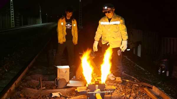 职工在线路上进行铝热焊点火焊接熔轨连接作业。谭育俊摄
