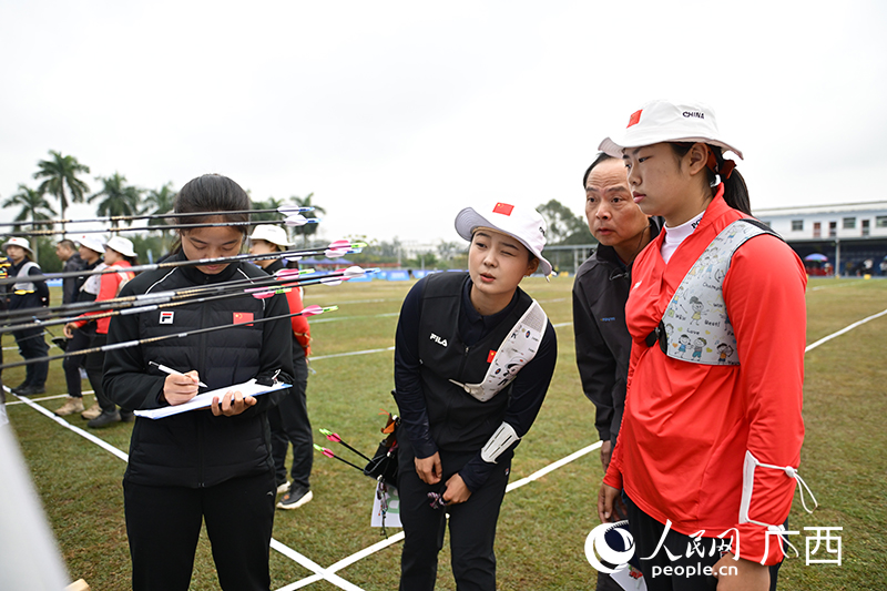 李佳蔓（右三）在和队员查看成绩。人民网 雷琦竣摄