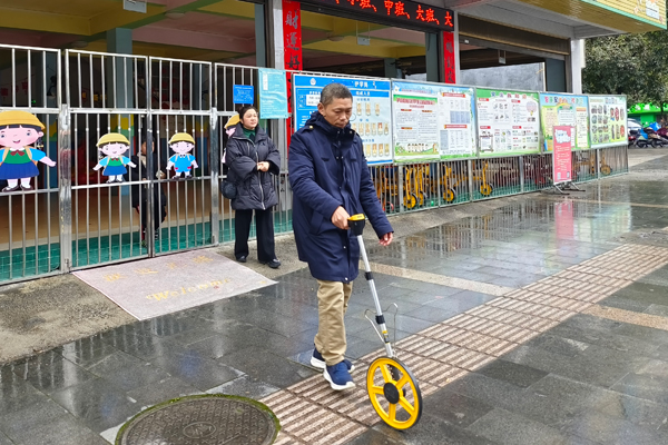 宜州烟草执法人员实地测量幼儿园到零售户的距离。覃业军摄