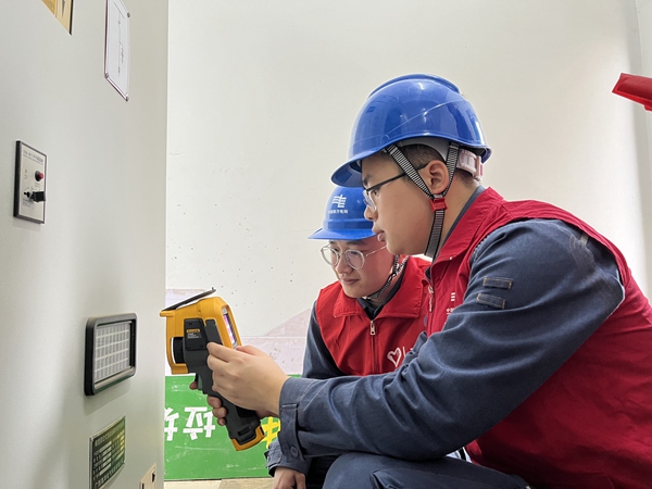南网蓝青年志愿者在钦州港经济技术开发区第四小学的配电房对电力设备进行巡视测温。王雄摄