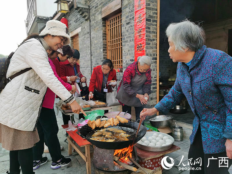 柳州市民在鱼峰区白沙镇购买当地特色小吃。人民网 付华周摄