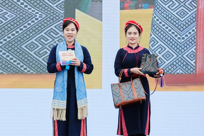 壮锦技艺传承人李素英（左一）及其女儿展示手工壮锦包具。龙州县委宣传部供图