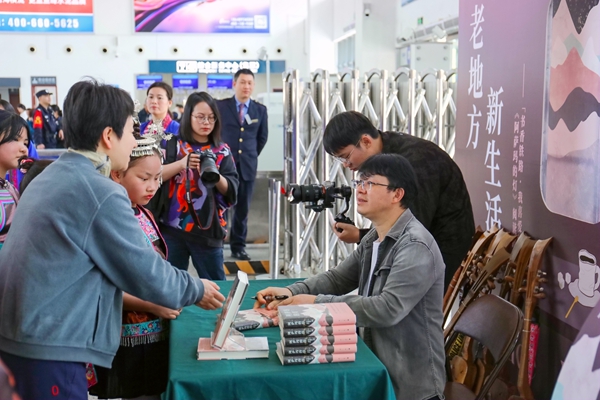 作家杨仕芳在三江南站为旅客签赠书籍。郑长贤摄