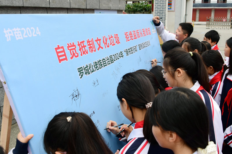 小学生在“绿书签行动”签名墙上签名。