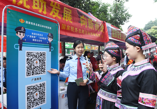玉林市税务局工作人员向少数民族群众宣传税费优惠政策，引导关注“广西税务”公众号。梁惠信摄