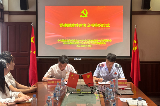 图为南宁市兴宁区税务局第一党支部书记与中国电信南宁兴宁分公司党支部书记签署党建联建共建协议书，税企合力，共促发展。（摄影：农婷菲）