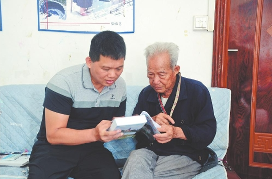 农廷兴（右）介绍收录在山歌集里的作品