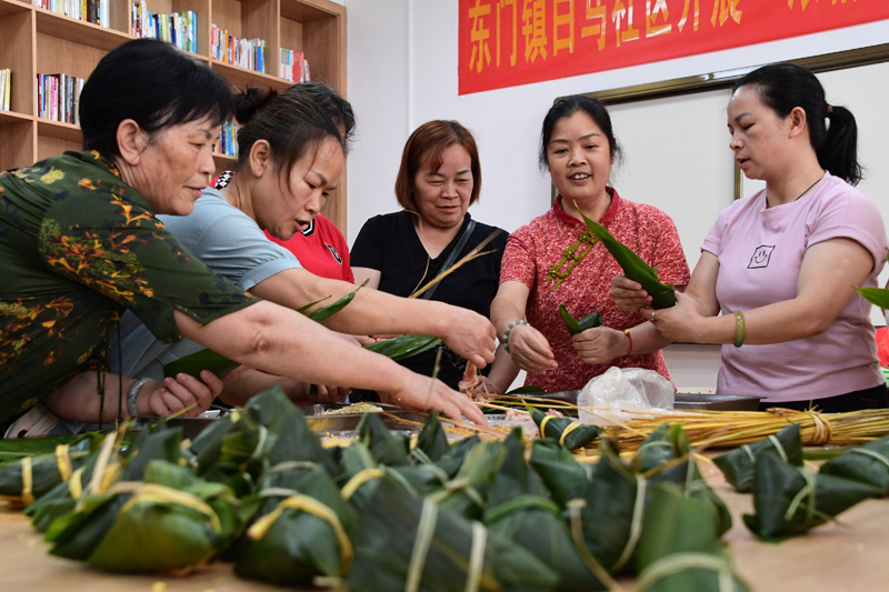 志愿者和居民们在包粽子。