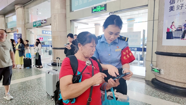 南宁站工作人员帮助旅客查找乘车信息。麦竹娴摄