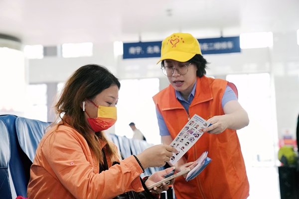 青年志愿者向旅客发放宣传折页。陈海婵摄