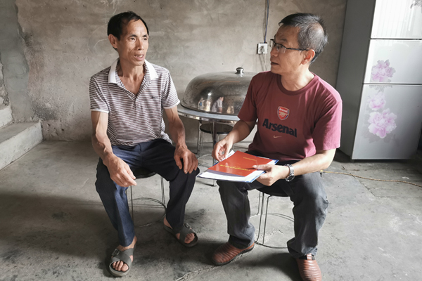 宜州烟草帮扶人（右）进村入户向群众宣传小额信贷政策。梁肖妮摄