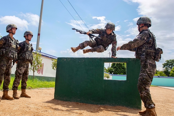 武警官兵在进行通过矮墙障碍训练。