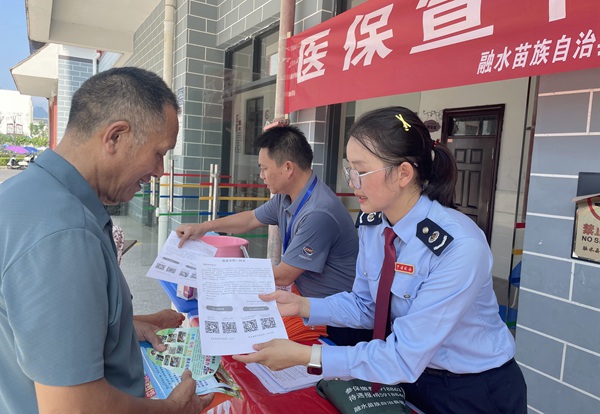 图为融水县税务和医保部门工作人员正在向学生家长解读最新的医保政策。融水县医疗保障局供图