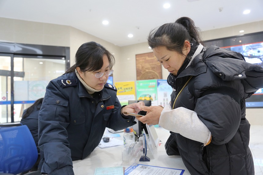 图为税务工作人员在办税大厅导税咨询台辅导缴费群众用手机缴纳医保费。梁新宗摄