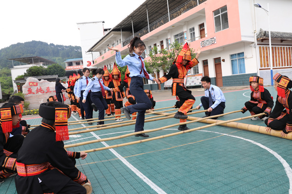 校园里，税务干部与瑶族学子携手完成竹竿舞表演。任斯林摄