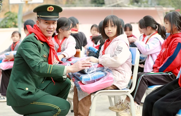 武警官兵为学生送上书包和校服。