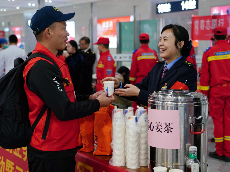 南宁东站工作人员为返乡的退役军人送上姜糖水。梁竞辉摄