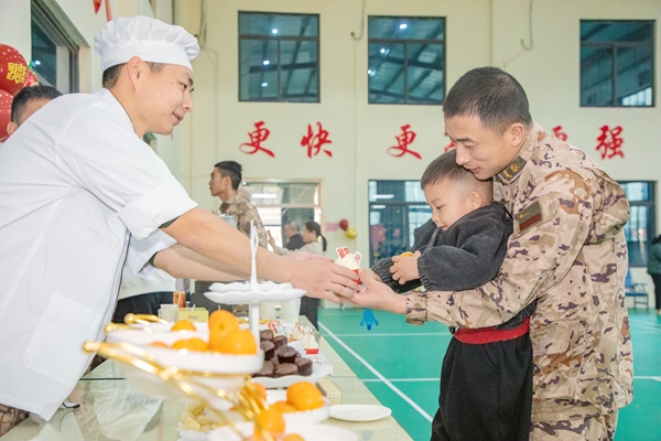 一名武警官兵正在帶家屬品嘗特色點心。