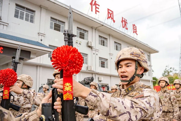 老兵将手中钢枪交于新兵。