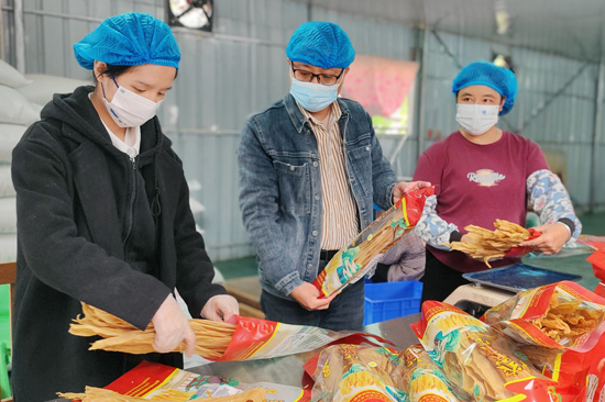 潘荣海（中）与村脱贫群众一起研究优化腐竹产品包装。吴培训摄