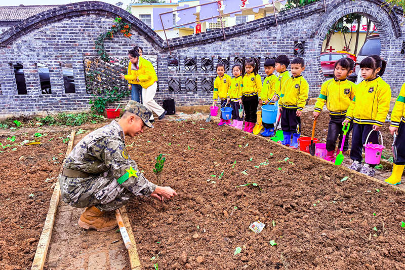 武警官兵給小朋友們演示和講解植樹要領。廖濤攝