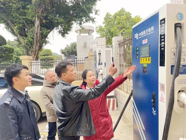 图为在新兴迷你服务区，柳州高速青年向司乘介绍新能源充电桩设备操作方式。