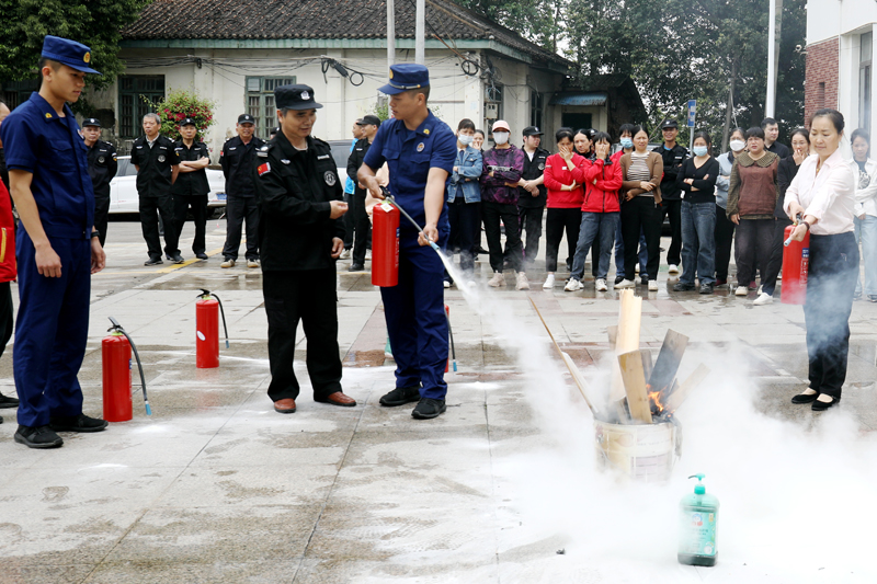 消防员现场演示干粉灭火器的正确使用方法。