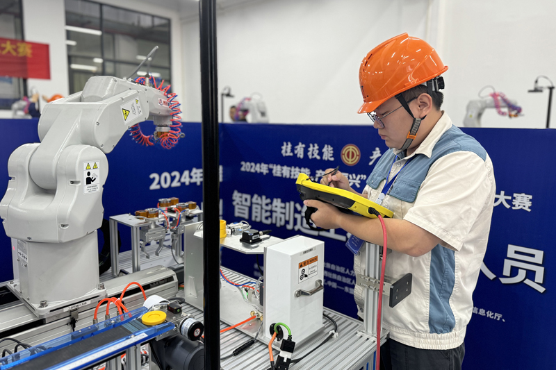 唐俊在比赛中使用编程调试机械手臂。广西中烟供图