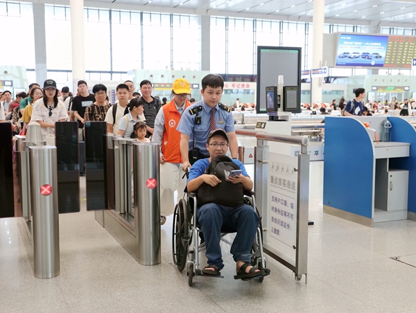 南宁东站客运值班员护送轮椅旅客乘车。麦竹娴摄