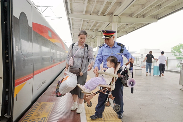 全州南站工作人员帮助携带儿童旅客乘车。卢穗萍摄