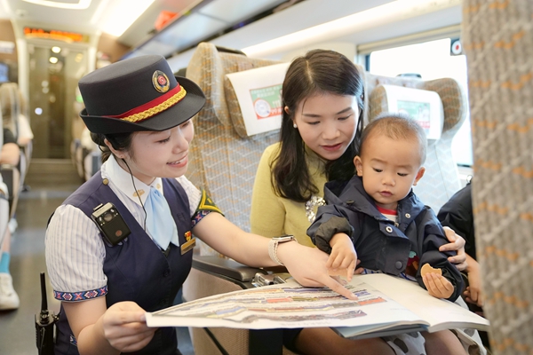 列车长梁祺与乘车的孩子互动。曾雨琦摄