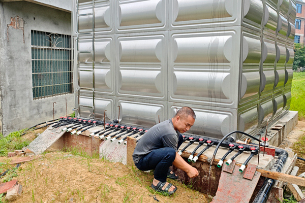 村民在储水罐旁用上了干净的自来水。银建华摄