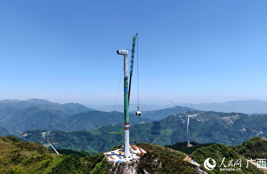 施工人员在吊装风力发电设备。