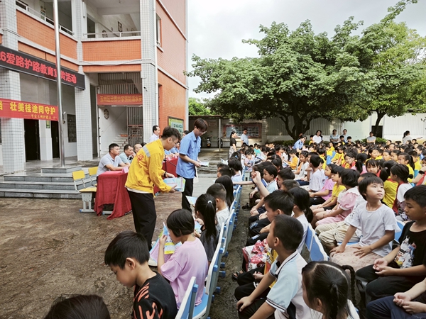 青年志愿者正在给学生们发放爱路护路知识手册。徐柯摄