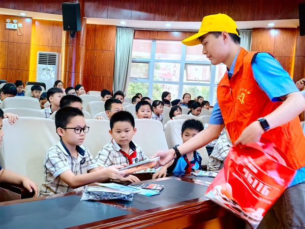 青年志愿者正在给学生们发放爱路护路知识手册。黄席摄