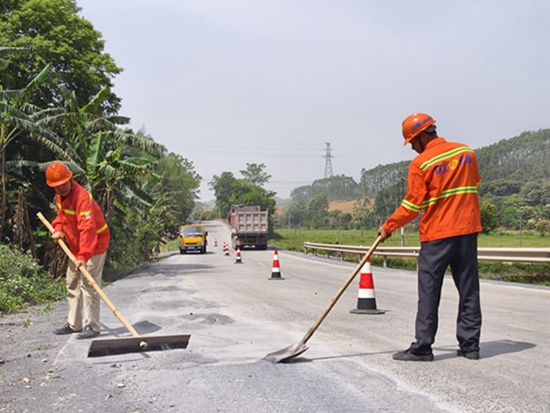 养护人员在省道312线清理路面石渣。梁建辉摄