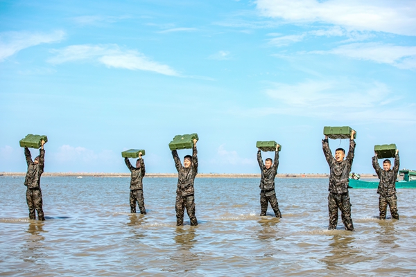 武警官兵在海水中进行负重训练。