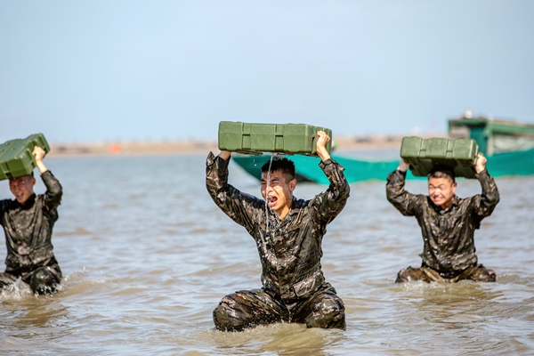 武警官兵在海水中进行负重训练。