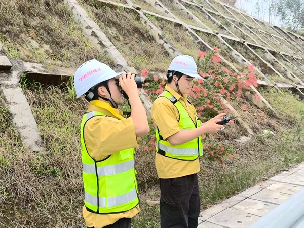 工作人员利用望远镜和无人机勘察边坡。