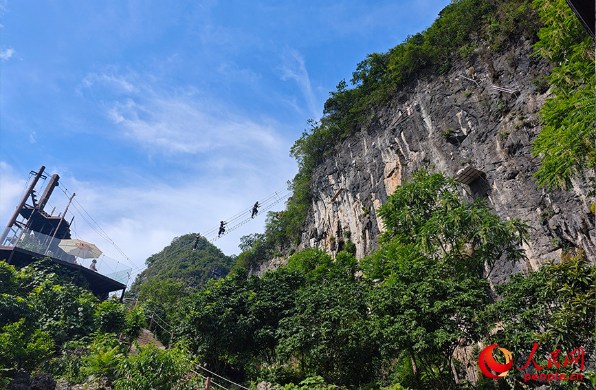 行進中國丨穿梭雲端峭壁 解鎖桂林山水新視角當游客穿戴好安全設備，爬上通往懸崖峭壁的“天梯”，懸於山間，腳下是美麗的田園風光，清澈的小河蜿蜒流淌，遠處是連綿的山峰，共同構成了一幅生機勃勃的山水田園畫卷。