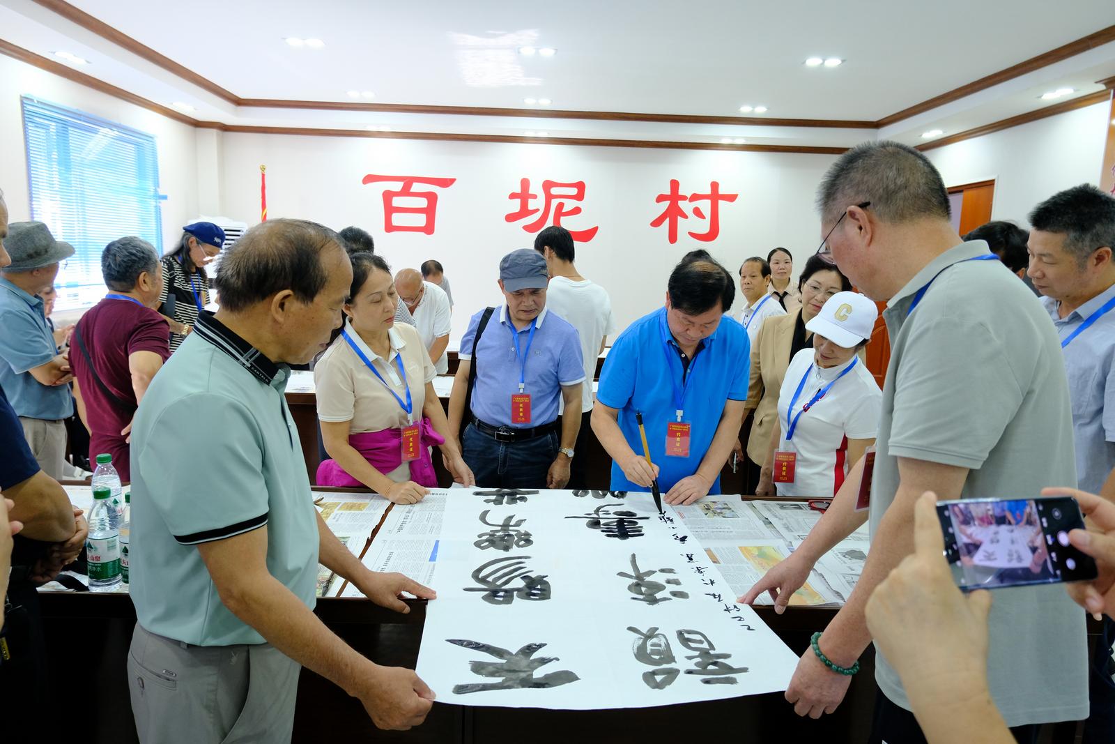 采风团成员在百坭村创作书法作品。