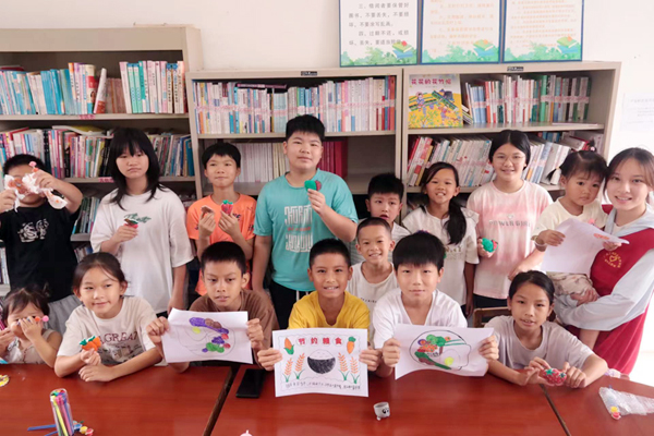 團隊成員與村內學生共同繪畫節約糧食卡紙。學校供圖